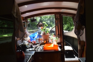 Light travels through a window in the background, depicting the front of a canal boat and a cluttered kitchen. Photo by Jennifer Ratcliffe 2020